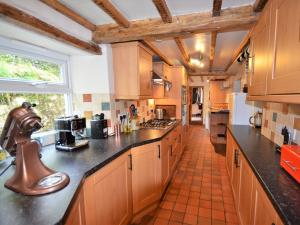 a large kitchen with wooden cabinets and black counter tops at 3 Bed in Llandovery 76381 in Ystrad-ffin