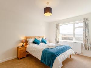 a bedroom with a bed with blue pillows and a window at 3 Bed in Dumfries 77430 in Auldgirth