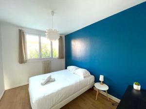 um quarto azul com uma cama branca e uma parede azul em Grand 2 chambres & parking em Besançon