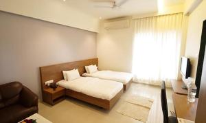 1 dormitorio con 2 camas y sofá en FabHotel Vovam Service Apartment, en Nashik