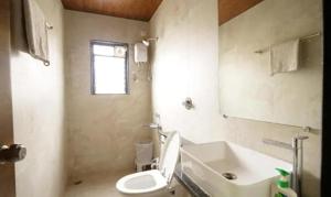 a bathroom with a white toilet and a sink at FabHotel Vovam Service Apartment in Nashik