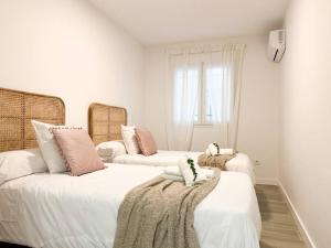 1 dormitorio con 2 camas y almohadas blancas y rosas en Apartamentos Gredos 101, en Jaraíz de la Vera