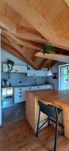 a kitchen with a wooden table and a black chair at Berg Apartments - Appartamento famigliare moderno in Stava