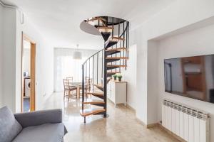 een wenteltrap in een woonkamer met een tafel bij First sea line nice duplex with terrace in Arenys de Mar