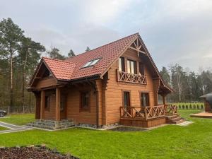 mały drewniany dom z dachem w obiekcie Dom Pod Lasem w Rydzewie