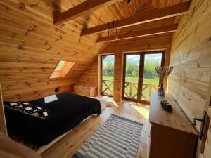Dormitorio de una cabaña de madera con cama y ventanas en Dom Pod Lasem en Rydzewo