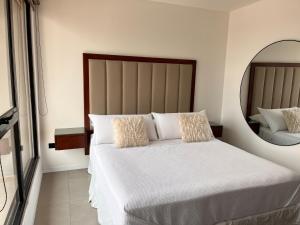 1 dormitorio con 1 cama blanca grande y espejo en Depto Lujo 1D Vista Privilegiada, en Santa Cruz de la Sierra