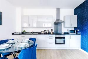 uma cozinha com armários brancos e uma mesa com cadeiras azuis em 2 Bedroom Manchester Gem Ancoats em Manchester
