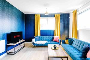 uma sala de estar com um sofá azul e uma televisão em 2 Bedroom Manchester Gem Ancoats em Manchester