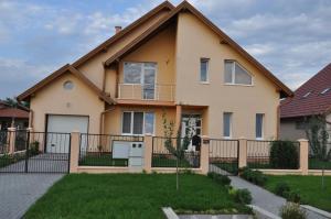 a house with a fence in front of a yard at Maros Vendégház in Mórahalom