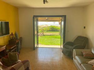ein Wohnzimmer mit einem Sofa und einer Glasschiebetür in der Unterkunft Casa Amarela a Beira Mar entre Arroio do Sal e Torres in Arroio do Sal
