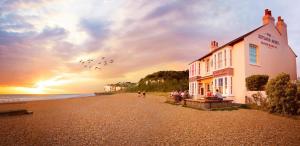 a group of birds flying over a building on a beach at 73 Palm Lodge in Kingsdown