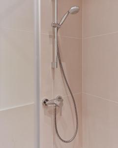 a shower with a shower head in a bathroom at Stylish & Modern Apartment - Private Garden & Free Parking in Vienna