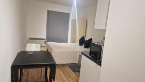 倫敦的住宿－Compact living cosy studio flat in london，一间卧室配有一张床、一张桌子和一台电视。