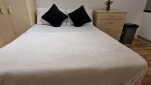 a bedroom with a white bed with black pillows at Compact living cosy studio flat in london in London