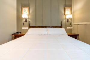 イルンにあるHotel Alcazar Irunの2つの照明付きの客室内の大きな白いベッド