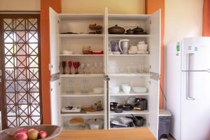 a kitchen with a white cabinet filled with dishes at Sítio da Vovó Dinha in Contagem