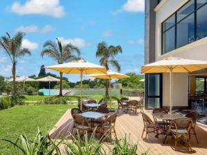 a patio with tables and chairs with umbrellas at The Regency Aparthotel in Pretoria