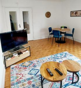 uma sala de estar com duas mesas e uma televisão de ecrã plano em Bel appartement à 9 minutes de Paris em Bois-Colombes