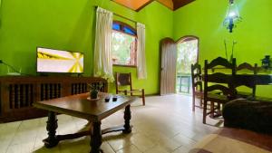 a living room with green walls and a wooden table at Casa de Campo - Condomínio Arco Íris in Atibaia