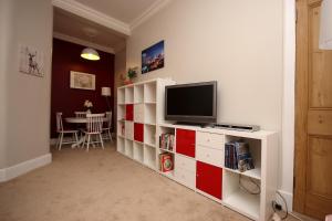 a living room with a television on a red and white cabinet at Hamish's Hame Edinburgh Licence No EH 69774 P in Edinburgh