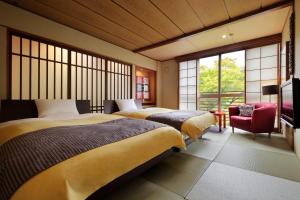 a bedroom with two beds and a red chair at Yamayuri no Yado in Hanamaki +183 photos
