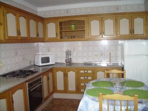 cocina con armarios de madera y mesa con microondas en Apartamento la Fragata Nerja, en Nerja