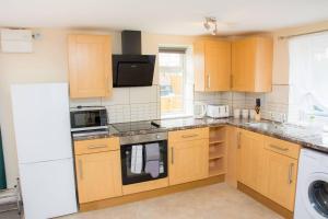 a kitchen with wooden cabinets and a white appliance at Charming 1-Bed Apartment in Stroud in Stroud