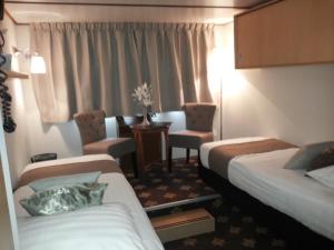 ein Hotelzimmer mit 2 Betten, einem Tisch und Stühlen in der Unterkunft Fairtours Hotelschiff Rex Rheni *** in Düsseldorf