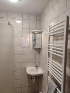 a white bathroom with a sink and a mirror at Thermál Panzió Kiskunmajsa in Kiskunmajsa