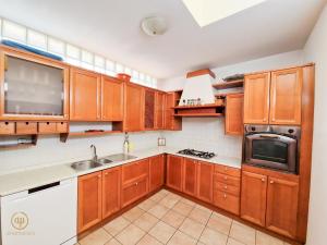 een keuken met houten kasten, een wastafel en een magnetron bij Holiday House Srečka in Izola