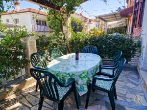 a table with four chairs and a bottle of wine at Holiday House Srečka in Izola