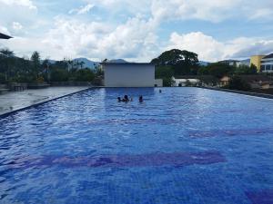 3 Personen schwimmen in einem großen Pool mit blauem Wasser in der Unterkunft Kinta Riverfront Ipoh - Laaman Homestay in Ipoh