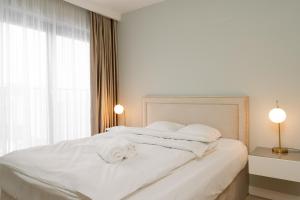 a white bedroom with a white bed with two lamps at RentPlanet - Apartament Ślężna in Wrocław