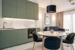 uma cozinha com armários verdes e uma mesa e cadeiras em RentPlanet - Apartament Ślężna em Breslávia