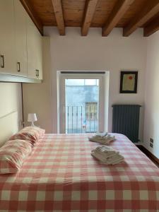 1 dormitorio con 1 cama con manta a cuadros y ventana en appartamento Marsala, en Brescia