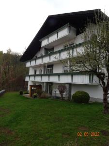 a white building with a black roof and a yard at Pension Anderl in Bodenmais