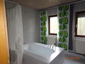 uma banheira na casa de banho com azulejos verdes e brancos em Pension Anderl em Bodenmais