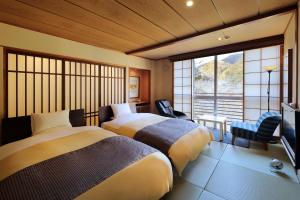 a bedroom with two beds and a tv and a window at Yamayuri no Yado in Hanamaki