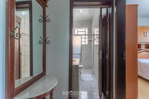 a bathroom with a mirror and a sink and a bed at Apto confortável Bem localizado em POA EBA0401 in Porto Alegre