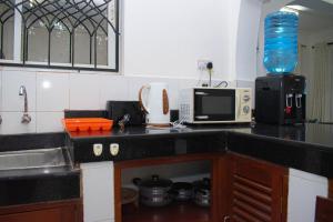 encimera de cocina con fregadero y microondas en Royal Palms Mtwapa Apartments, en Mtwapa