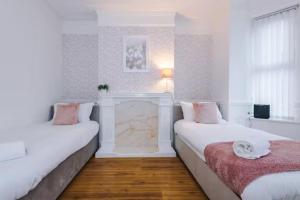 a white room with two beds and a fireplace at Spacious 4-Bed House Manchester in Manchester
