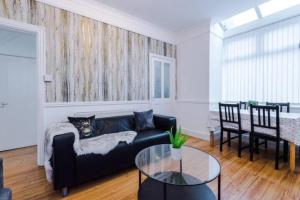 a living room with a black couch and a table at Spacious 4-Bed House Manchester in Manchester