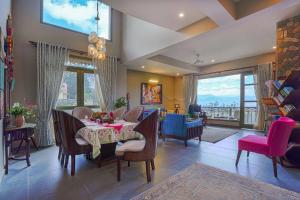 a dining room with a table and chairs with a view at SaffronStays Edelweiss Bluebell House - 3BR English home with Himalayan peak views, bonfire & reading nook in Rānīkhet