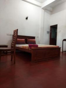 a large wooden bed in a room with a chair at New Dulmi Guest House. in Denipitiya