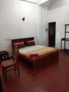 a bedroom with a large bed and a chair at New Dulmi Guest House. in Denipitiya