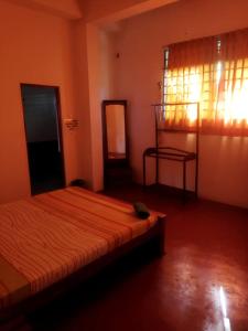 a bedroom with a bed in a room with a window at New Dulmi Guest House. in Denipitiya