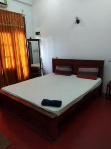 a bedroom with a large bed with white sheets and a mirror at New Dulmi Guest House. in Denipitiya