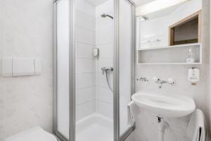 een witte badkamer met een douche en een wastafel bij Alpenrose Hotel and Gardens in Wilderswil