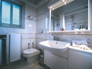 a white bathroom with a sink and a toilet at Yianni's Home-Comfort Apartment in Volos in Volos